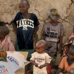 insult-to-injury:-african-kids-receive-overstock-harris-walz-hats-to-wear-with-their-yankees-world-championship-shirts