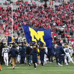 sherrone-moore-does-flag-planting-gesture-at-michigan-basketball-game,-one-week-after-beating-ohio-state