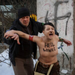 shocking-moment-topless-protester-posing-as-hitler-is-arrested-scrawling-swastikas-on-remnants-of-berlin-wall