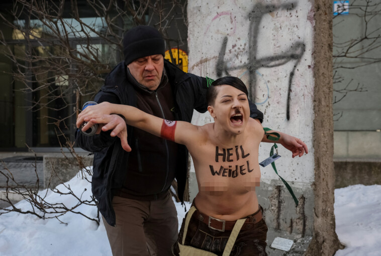 shocking-moment-topless-protester-posing-as-hitler-is-arrested-scrawling-swastikas-on-remnants-of-berlin-wall