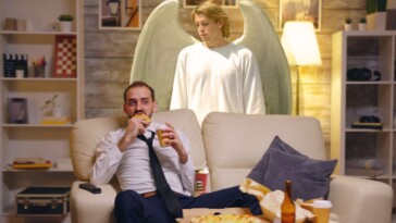 guardian-angel-dutifully-stands-over-man-watching-tv-to-make-sure-he-doesn’t-choke-on-his-pringles