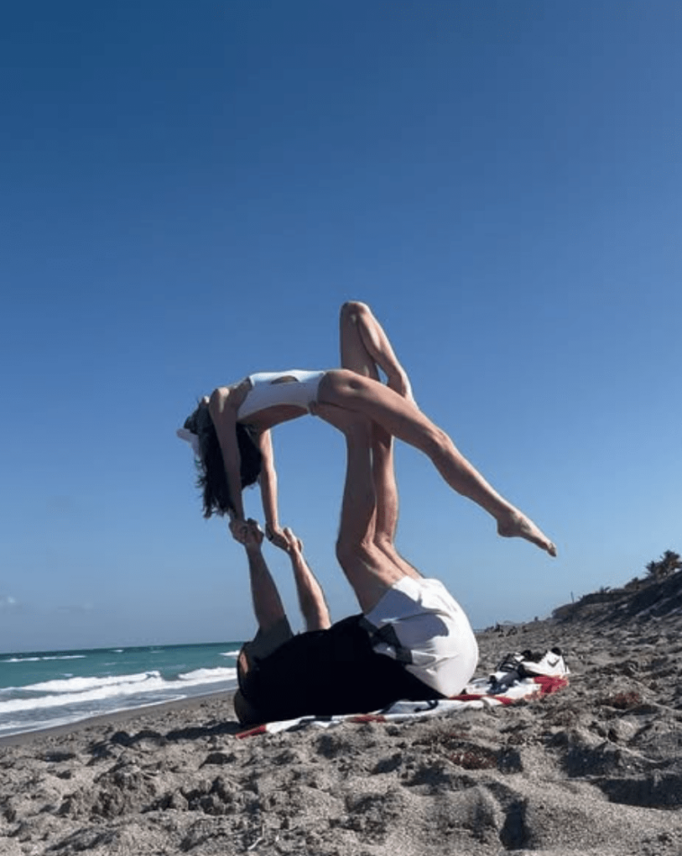 bill-belichick-helps-jordan-hudson-perform-wild-acrobatic-pose-on-beach
