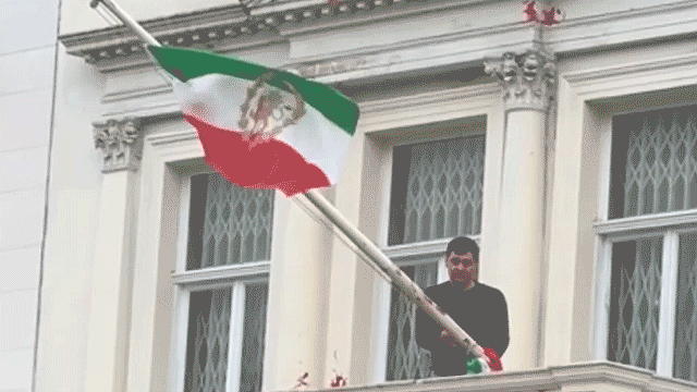 protester-scales-iranian-embassy-in-london,-tears-down-regime-flag,-hoists-pre-revolution-symbol