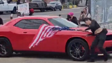 anti-ice-protester-hit-by-car-while-waving-upside-down-us-flag-outside-delaney-hall