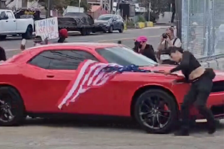 anti-ice-protester-hit-by-car-while-waving-upside-down-us-flag-outside-delaney-hall