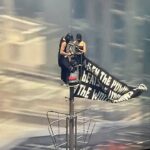 two-people-climb-to-the-top-of-empire-state-building-with-massive-banner