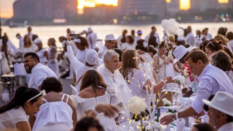 dinner-party-has-guests-bringing-tables,-dressing-in-white-and-learning-location-last-minute
