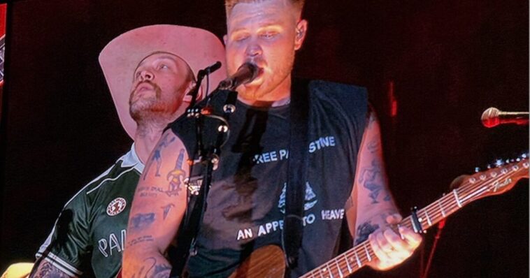 zach-bryan-‘bud-lights’-himself-—-us.-navy-vet-and-his-band-members-wear-t-shirts-with-unpopular-woke-messages-on-stage